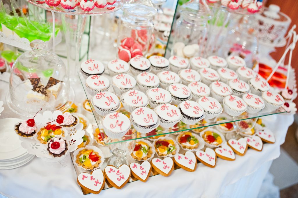 Different sweets and cupcakes at catering wedding reception table.