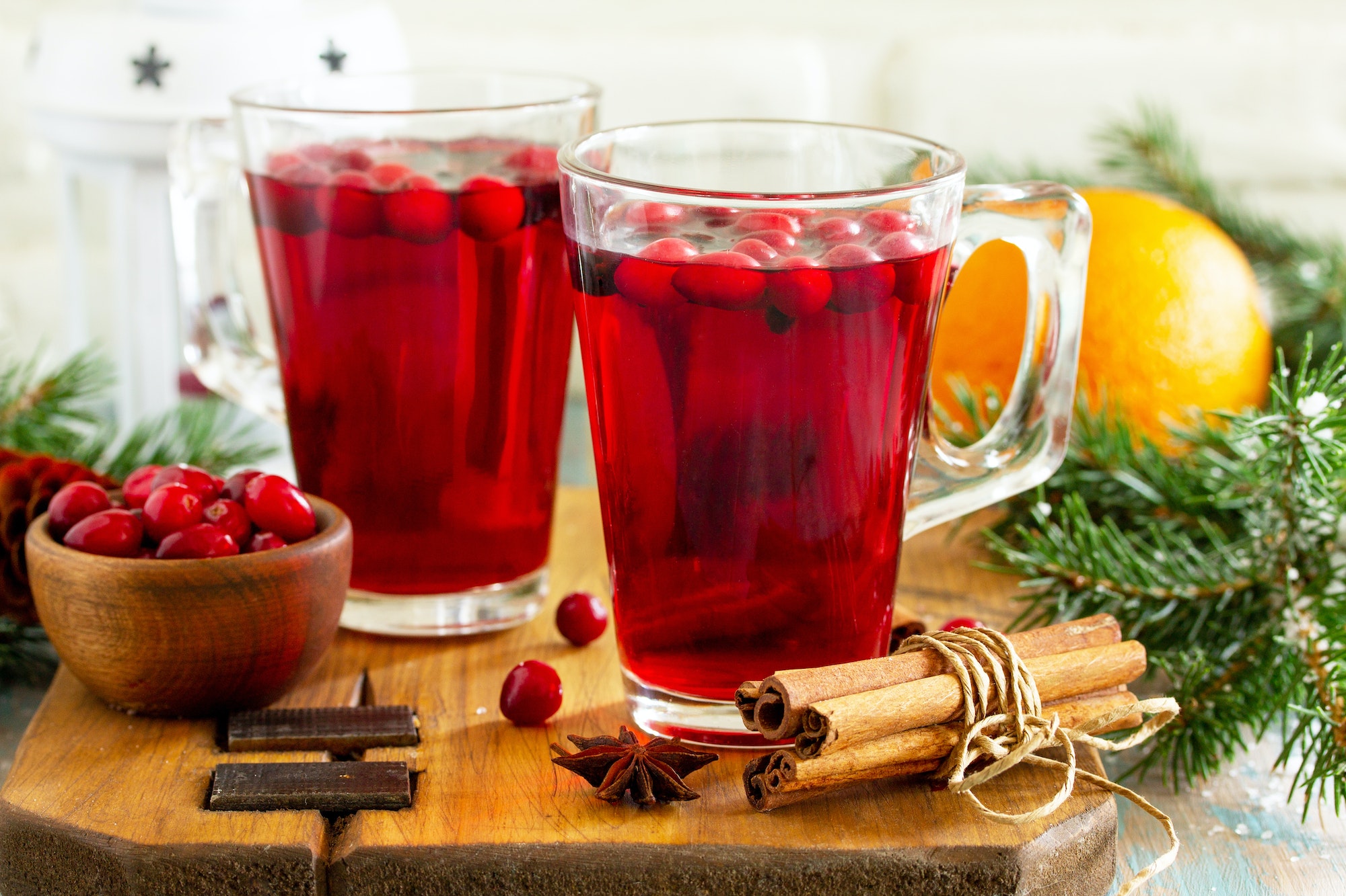 Christmas, Thanksgiving drinks. Hot winter drink with cranberries and cinnamon on wooden table.