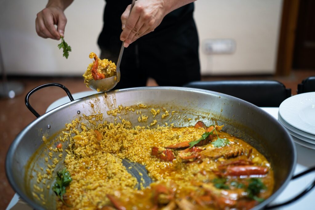 Chef serving paella to a group of diners for a meal