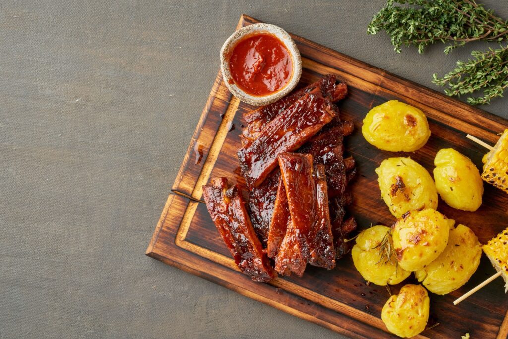 Spicy barbecue pork ribs, corn ears and crushed smashed potatoes.American Cuisine.