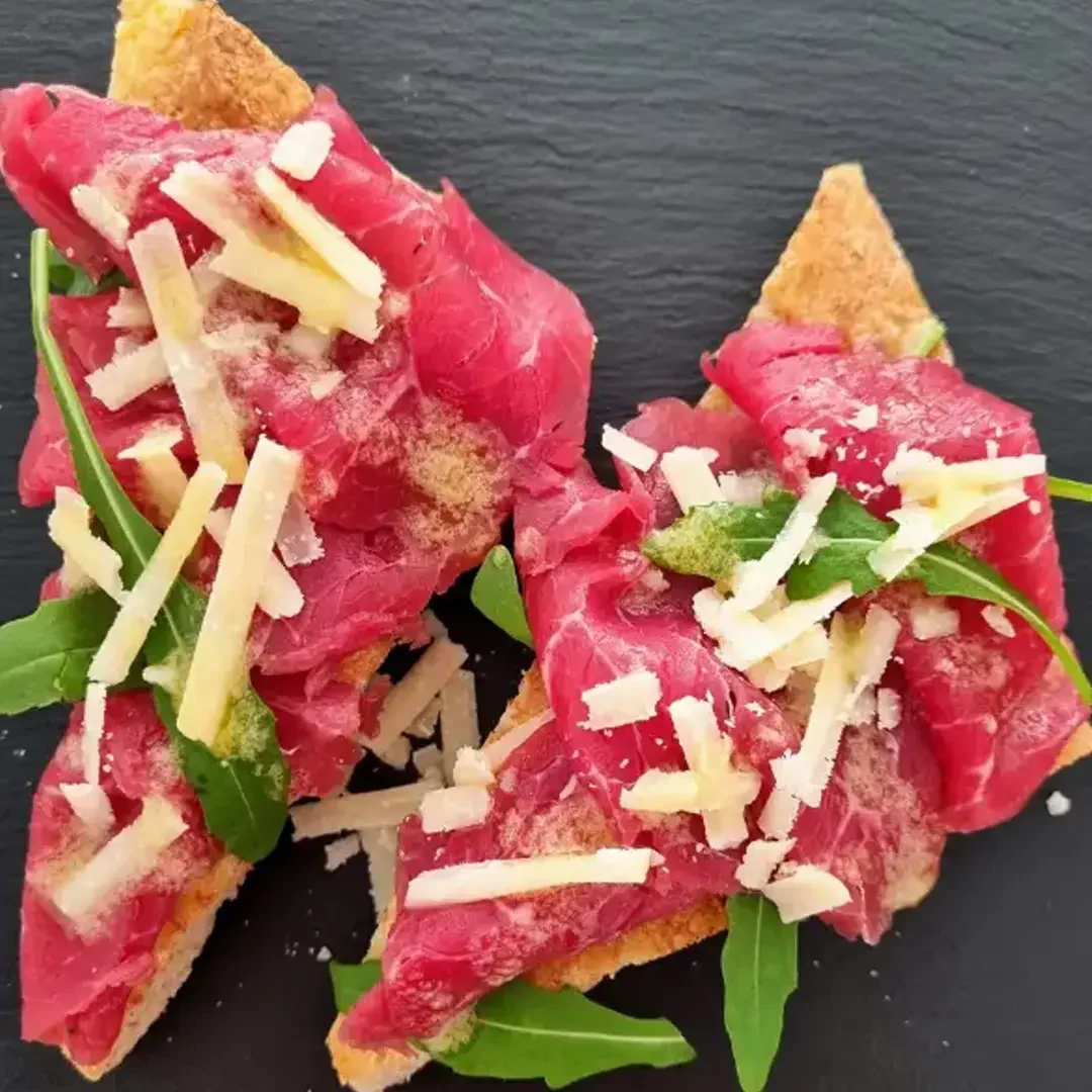 Canapé de carpaccio de ternera con rúcula y parmesano