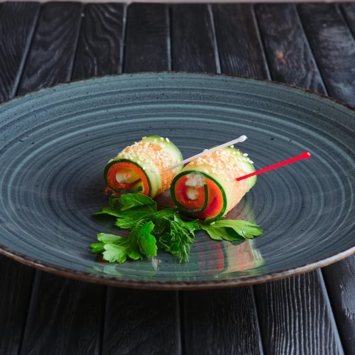 Appetizer for reception. Piece of salmon rolled in long slice of cucumber topped with sesame