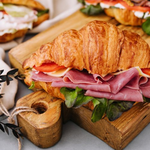Delicious croissant sandwich on wooden board